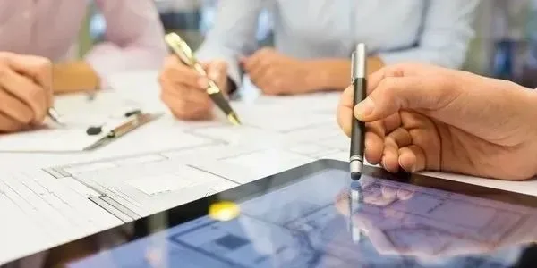 Two people collaborating using pen and tablet on plans.